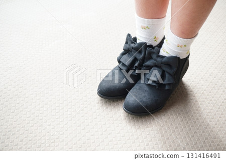 A stylish photo of cute feet in a close-up of short boots with large black ribbons 131416491