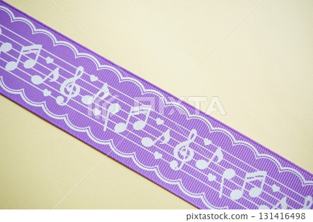 A diagonal photo of a purple ribbon with a white musical note design. 131416498