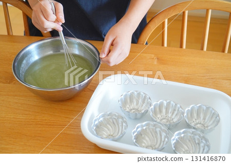 一張照片顯示，一個孩子正在用攪拌器和排列在白色托盤中的模具攪拌青蘋果果凍，展示家庭烘焙 131416870