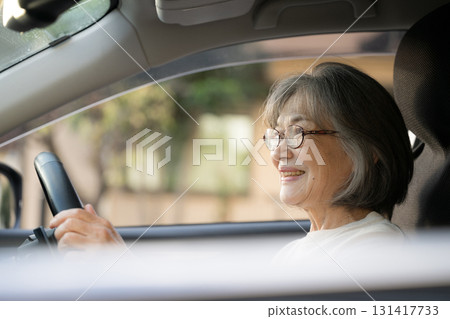 Smiling elderly woman driving a car in the evening 131417733