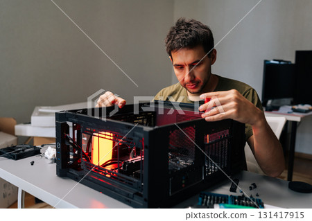 Computer technician installing components inside desktop computer case, illuminated by red light, performing maintenance or upgrade. Concept of computer hardware, repairing, upgrade and technology. Computer technician installing components inside desktop computer case, illuminated by red light, performing maintenance or upgrade. Concept of computer hardware, repairing, upgrade and technology. 131417915