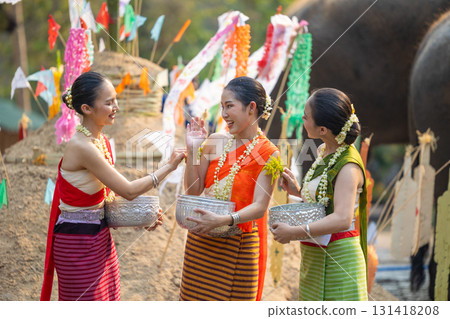 Songkran festival. Northern Thai people in Traditional clothes dressing splashing water together in Songkran day cultural festival with sand pagoda and colorful paper flag. Songkran festival. Northern Thai people in Traditional clothes dressing splashing water together in Songkran day cultural festival with sand pagoda and colorful paper flag. 131418208