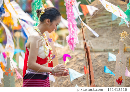Songkran festival. Northern Thai people in Traditional clothes dressing carrying sand into temple to build sand pagoda and decoration with colorful paper flag. 131418216