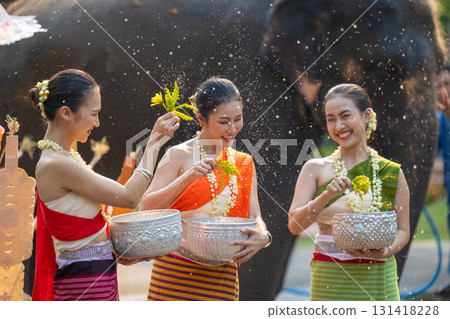 Songkran festival. Northern Thai people in Traditional clothes dressing splashing water together in Songkran day cultural festival with elephant background. 131418228