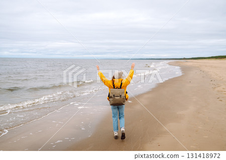 Attractive woman on windy cold beach. Beautiful tourist woman in stylish clothes enjoys life by sea. Attractive woman on windy cold beach. Beautiful tourist woman in stylish clothes enjoys life by sea. 131418972