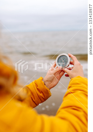 Woman traveler looking for directions with a compass on beach. Active lifestyle. Adventure concept. 131418977