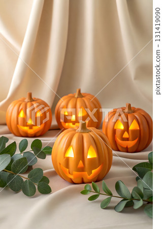 Four glowing pumpkins arranged with greenery for a festive fall decoration 131419090