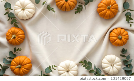 Decorative arrangement of pumpkins and greenery on a light fabric background for autumn celebration 131419097