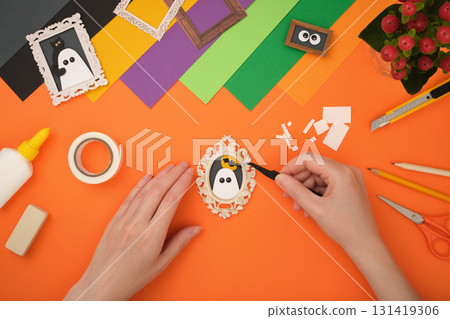 The process of creating a Halloween craft. Glue the bat onto the outline of the moon. 131419306