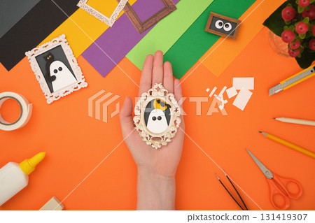 The finished paper craft. A portrait of a ghost with the silhouette of the moon and a bat in a frame. The finished paper craft. A portrait of a ghost with the silhouette of the moon and a bat in a frame. 131419307