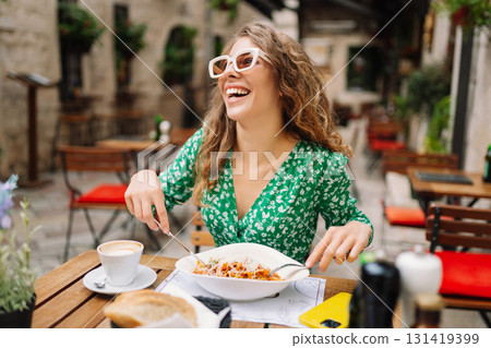 Portrait of smiling woman eating pasta at cozy italian restaurant outdoors. Tourism, food and drink 131419399