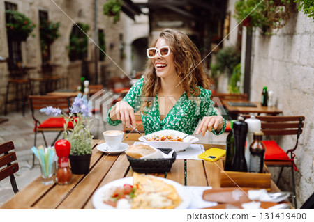Portrait of smiling woman eating pasta at cozy italian restaurant outdoors. Tourism, food and drink Portrait of smiling woman eating pasta at cozy italian restaurant outdoors. Tourism, food and drink 131419400
