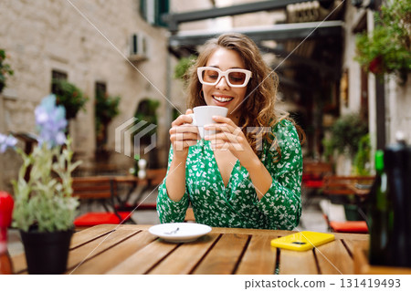 Young woman tourist drinks coffee in the old town in summer trip. People, fashion, lifestyle Young woman tourist drinks coffee in the old town in summer trip. People, fashion, lifestyle 131419493
