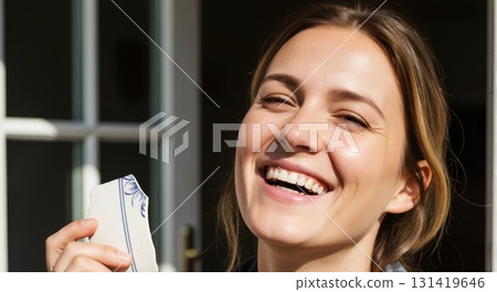 Happy young woman laughing in bright sunlight. Candid portrait holding a broken porcelain shard. Good luck and joy concept 131419646