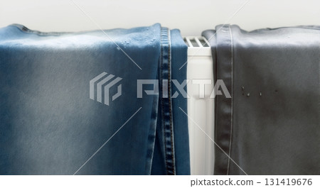 Wet blue and grey denim jeans drying on a white radiator. Household laundry and clothing care concept 131419676