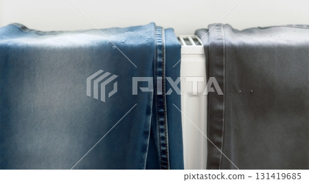 Wet blue and grey denim jeans drying on a white radiator. Household laundry and heating concept Wet blue and grey denim jeans drying on a white radiator. Household laundry and heating concept 131419685
