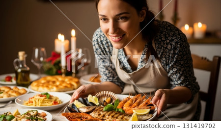 Woman serving seafood platter at an Italian dinner table. Home cooked meal with pasta and candles. Festive celebration concept 131419702