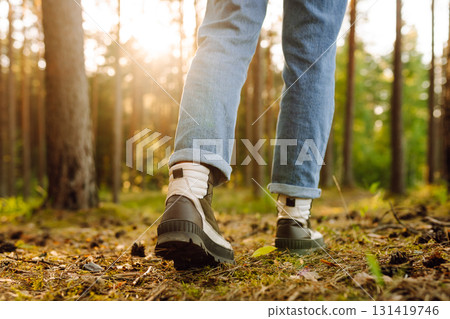 Feet of an adult wearing boots to travel walking in the forest. Feet walking in outdoor nature Feet of an adult wearing boots to travel walking in the forest. Feet walking in outdoor nature 131419746