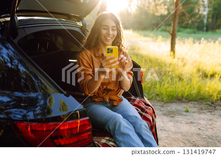 Young woman enjoys a sunny day outdoors while sitting in her car. Travel, weekend, nature, relax 131419747