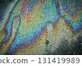 Oil slick on dark asphalt surface creating a vibrant, iridescent, abstract texture with rainbow colours. 131419989