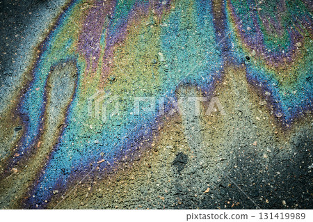 Oil slick on dark asphalt surface creating a vibrant, iridescent, abstract texture with rainbow colours. 131419989
