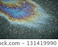 Oil slick creating iridescent rainbow pattern on asphalt 131419990