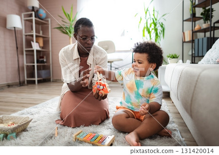 Grandmother and grandson playing with wooden toy at home Grandmother and grandson playing with wooden toy at home 131420014