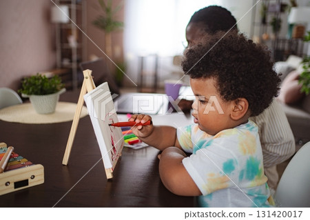 African american toddler drawing on easel at home African american toddler drawing on easel at home 131420017
