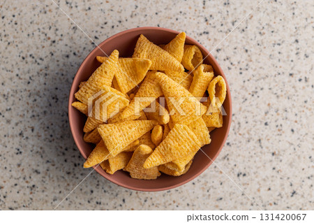 Bugles snack. Cone corn chips in bowl on kitchen table. Top view. 131420067