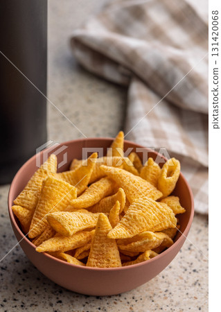 Bugles snack. Cone corn chips in bowl on kitchen table. 131420068