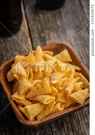 Bugles snack. Cone corn chips in bowl on wooden table. 131420073