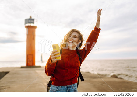 Young woman enjoying nature by the waterfront during a cloudy day by a lighthouse. Blogging concept 131420209
