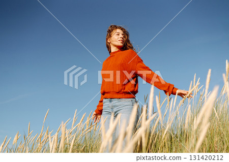 Happy woman enjoying nature outdoors in tall grass. Flying hairs. Outdoor. Fashion style. 131420212