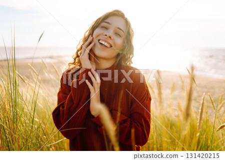 Happy woman enjoying nature outdoors in tall grass. Flying hairs. Outdoor. Fashion style. 131420215