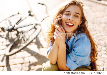 Beautiful smiling woman sitting next to bike on the street city. Adventure Concept 131420645
