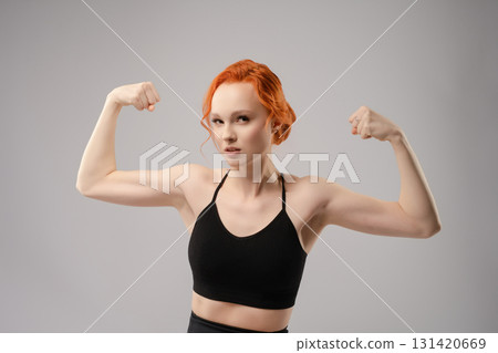 Confident woman with red hair and strong physique under projector light Confident woman with red hair and strong physique under projector light 131420669