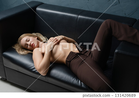 Woman relaxing on a black couch in a beauty studio with a serene expression Woman relaxing on a black couch in a beauty studio with a serene expression 131420689
