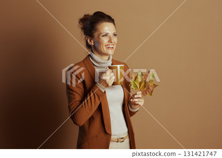 Smiling Businesswoman with Autumn Leaves and Cozy Mug Smiling Businesswoman with Autumn Leaves and Cozy Mug 131421747