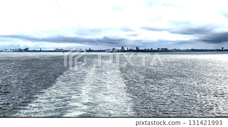 Calm Waterway Reveals Distant City Skyline Under Moody Clouds 131421993