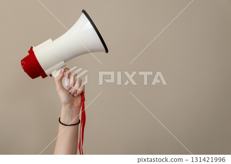 Hand holding megaphone against neutral background 131421996