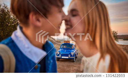 Romantic couple smiling close to each other with retro blue car in background 131422033