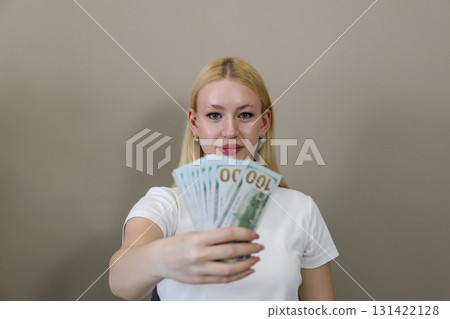 Woman presenting fan of hundred dollar bills toward camera 131422128