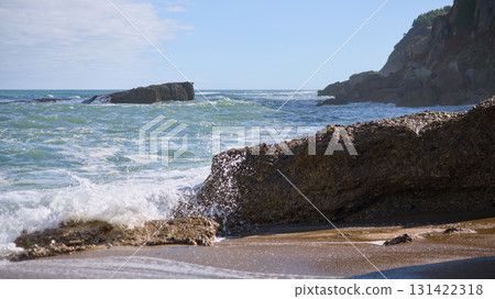 Waves hitting rocky beach with golden sand and blue horizon Waves hitting rocky beach with golden sand and blue horizon 131422318
