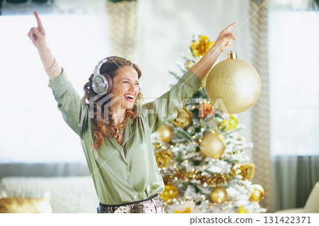 Joyful Woman Dancing with a Golden Christmas Ornament 131422371