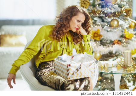 Thoughtful Woman Reflects by Christmas Tree Thoughtful Woman Reflects by Christmas Tree 131422441