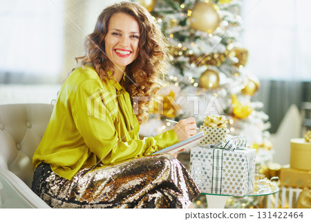 Cheerful Woman Writes Holiday List by Christmas Tree 131422464
