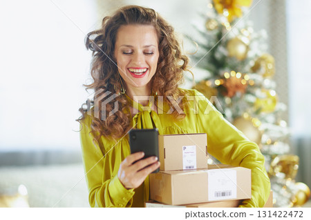 Cheerful Woman with Holiday Packages and Smartphone Cheerful Woman with Holiday Packages and Smartphone 131422472
