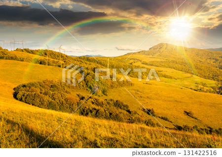 countryside mountain landscape in autumn at sunset. rural field on green hills. beautiful scenery with grassy meadows and forested slopes in highland under blue sky. scenic view in evening light 131422516