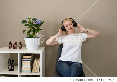 Joyful woman enjoying music in headphones at home Joyful woman enjoying music in headphones at home 131422602