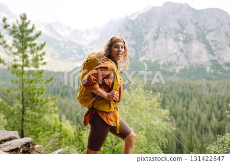 Smiling traveler with a bright backpack on a hiking mountain trail. Active lifestyle. Smiling traveler with a bright backpack on a hiking mountain trail. Active lifestyle. 131422847